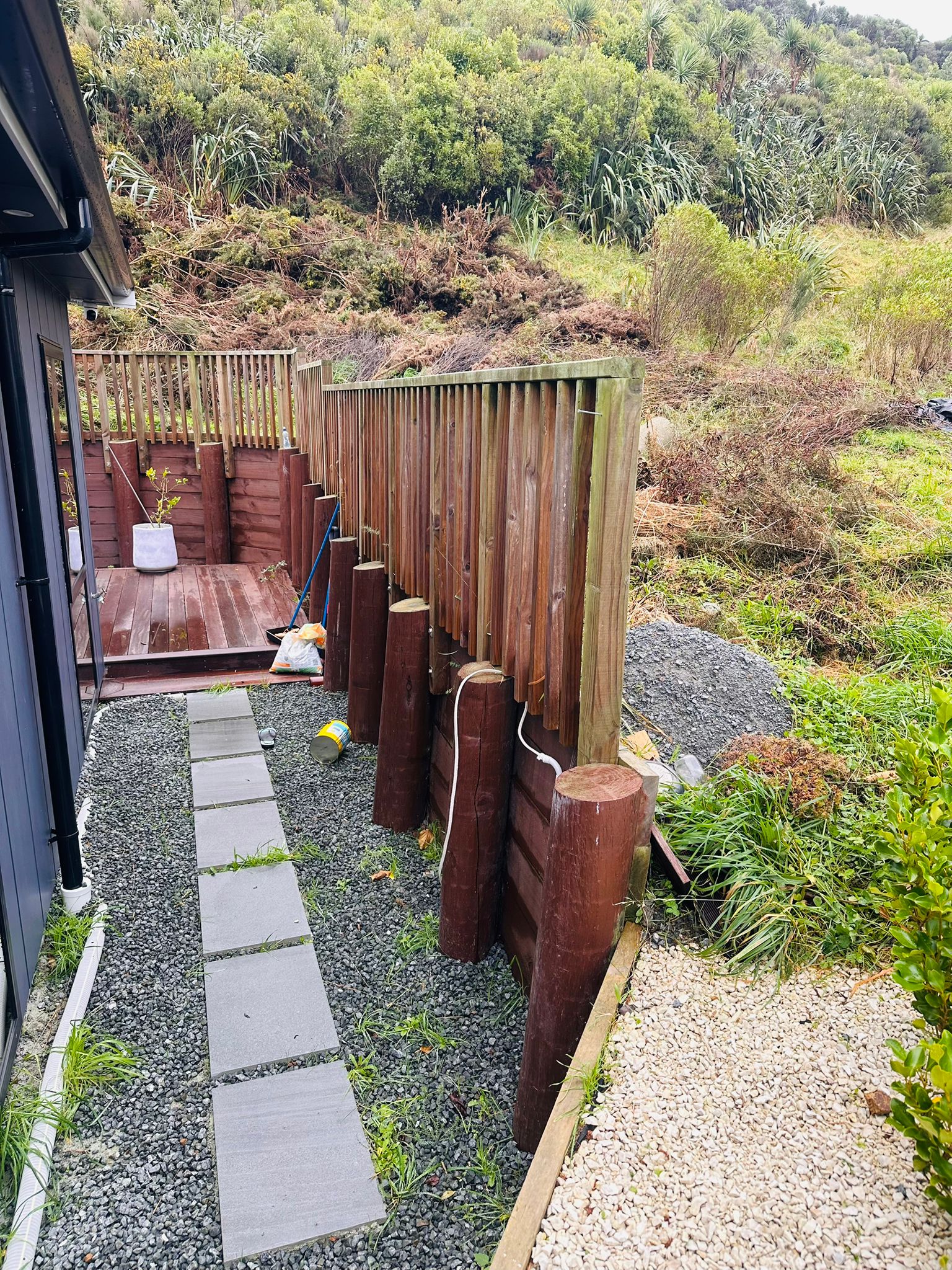 Pole retaining wall and gravel path on a cleared slope